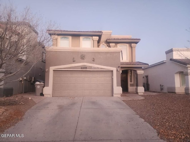 mediterranean / spanish home with driveway, a tile roof, an attached garage, and stucco siding