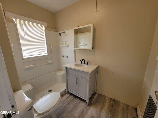 bathroom with hardwood / wood-style flooring, vanity, toilet, and walk in shower