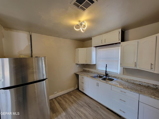 kitchen featuring stainless steel refrigerator, white cabinetry, sink, and light hardwood / wood-style floors