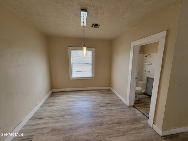 unfurnished dining area featuring light hardwood / wood-style floors and a textured ceiling