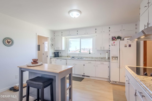 kitchen with sink, white appliances, a breakfast bar area, white cabinets, and light wood-type flooring