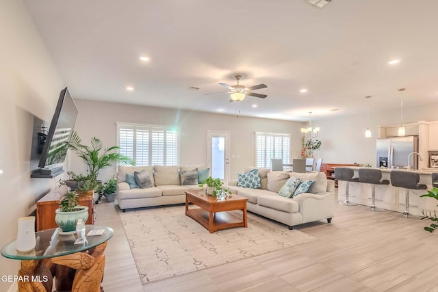 living room with a healthy amount of sunlight and ceiling fan with notable chandelier