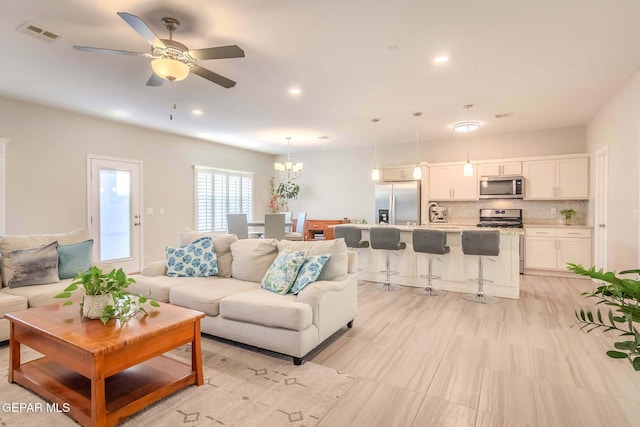 living room with ceiling fan with notable chandelier