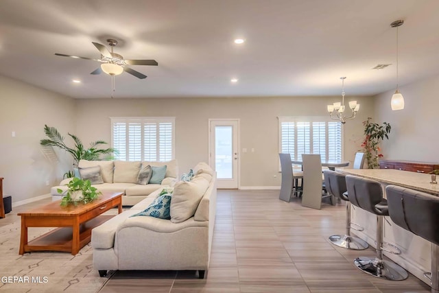 tiled living room featuring ceiling fan with notable chandelier