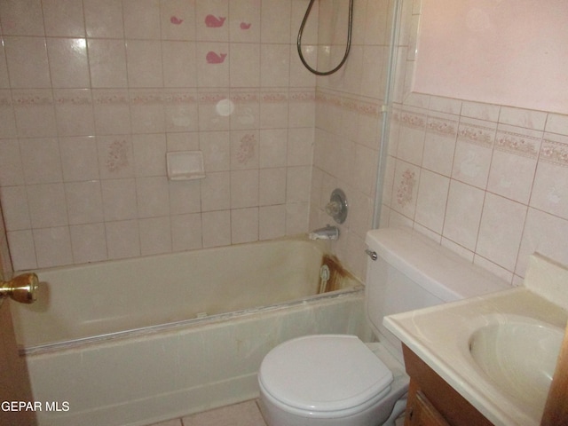 full bathroom featuring tile patterned floors, vanity, tiled shower / bath combo, tile walls, and toilet