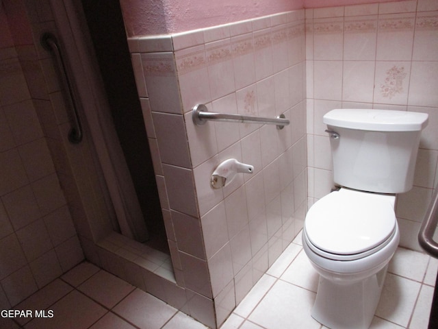 bathroom featuring toilet, a shower, and tile walls