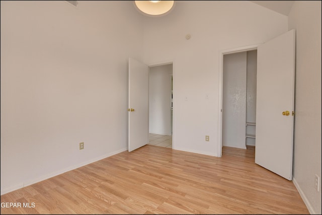 unfurnished bedroom with light hardwood / wood-style floors and a high ceiling