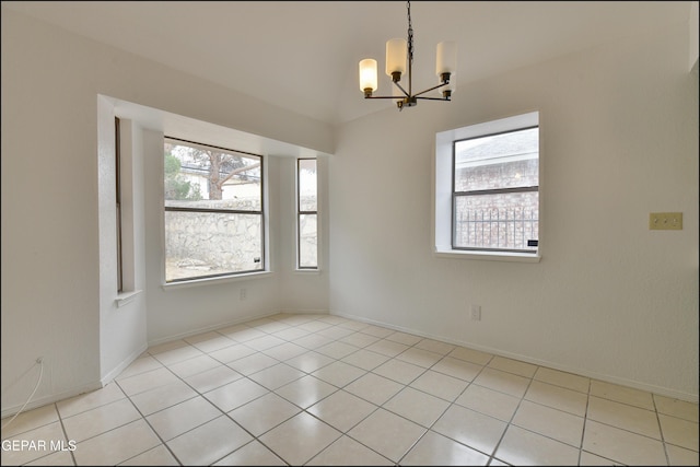 tiled spare room with an inviting chandelier