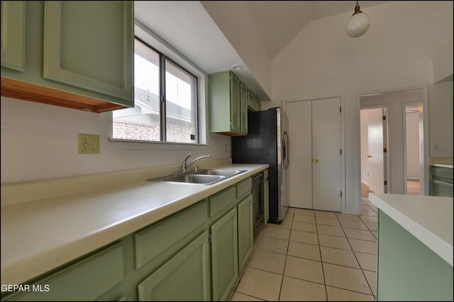 kitchen featuring lofted ceiling, sink, light tile patterned floors, black dishwasher, and green cabinets