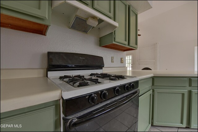 kitchen with white range with gas cooktop, ventilation hood, green cabinets, and light tile patterned floors