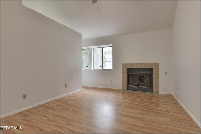 unfurnished living room featuring a tile fireplace and light hardwood / wood-style floors