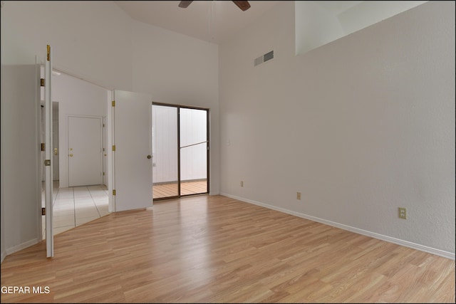 unfurnished room featuring a towering ceiling, ceiling fan, and light wood-type flooring