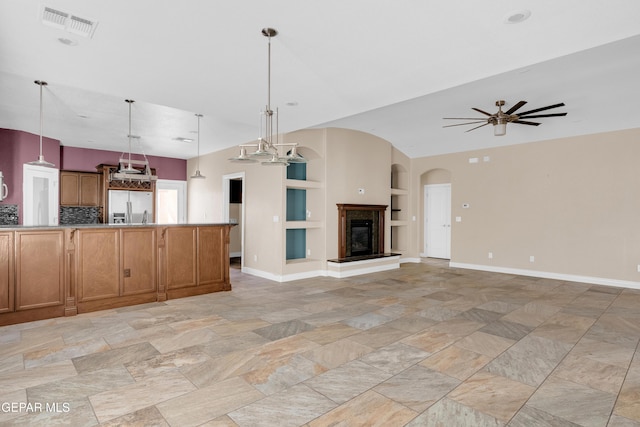 unfurnished living room featuring vaulted ceiling, built in features, and ceiling fan