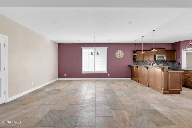 kitchen with decorative backsplash, kitchen peninsula, decorative light fixtures, and an inviting chandelier