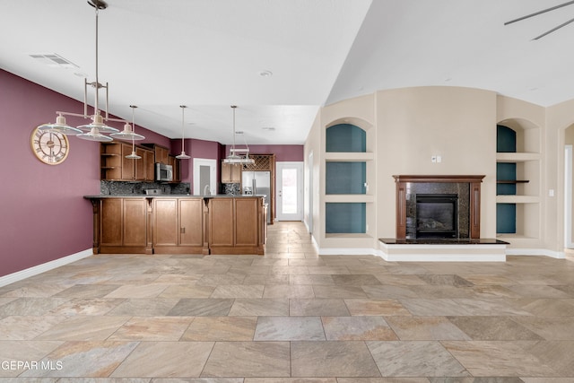 kitchen featuring a high end fireplace, appliances with stainless steel finishes, tasteful backsplash, built in shelves, and decorative light fixtures