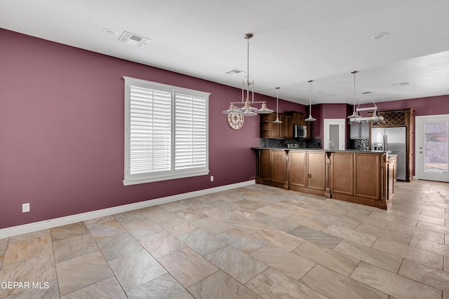 kitchen featuring pendant lighting, backsplash, kitchen peninsula, and stainless steel appliances