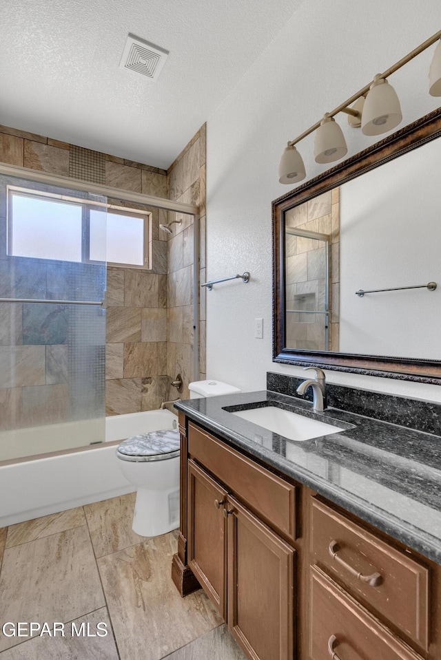 full bathroom with shower / bath combination with glass door, vanity, a textured ceiling, and toilet