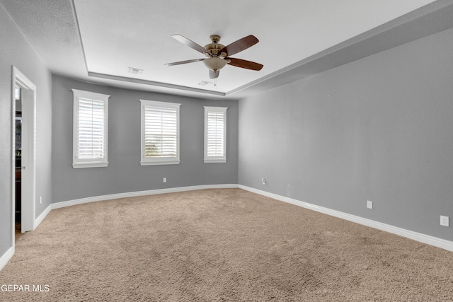 carpeted empty room featuring ceiling fan, a raised ceiling, and a textured ceiling