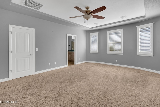 unfurnished room with carpet, ceiling fan, and a raised ceiling