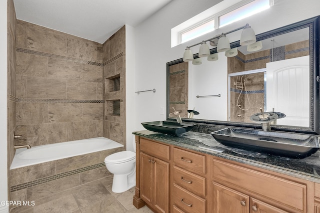 full bathroom featuring vanity, tiled shower / bath combo, and toilet