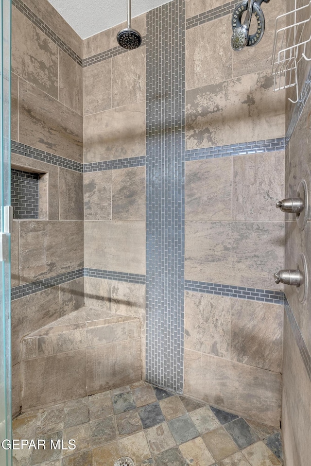 bathroom with a tile shower and a textured ceiling