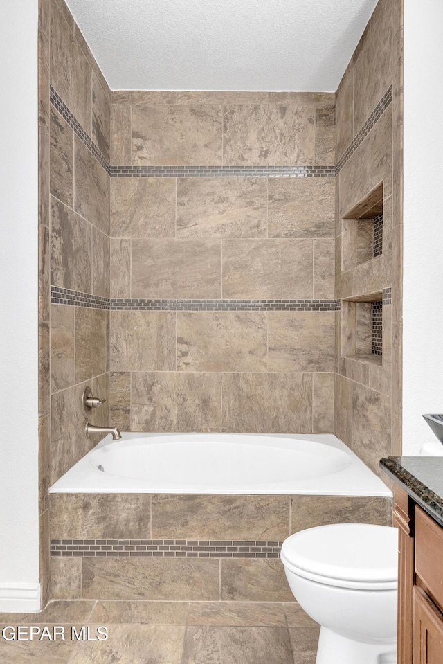 full bathroom with a textured ceiling, vanity, toilet, and tiled shower / bath