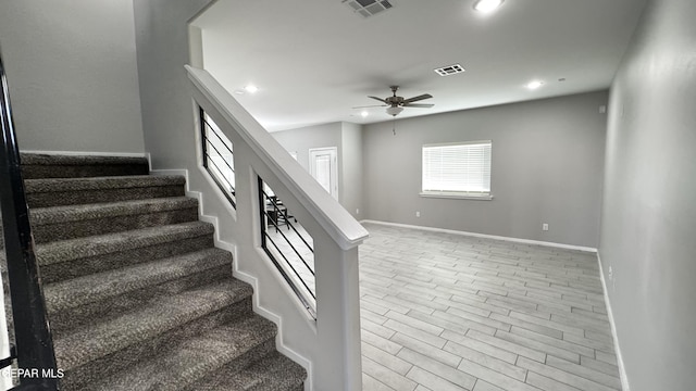 staircase featuring ceiling fan and wood-type flooring