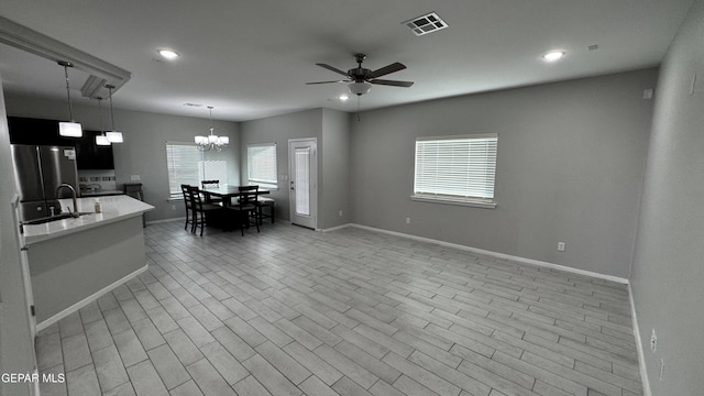 interior space featuring ceiling fan with notable chandelier, sink, stainless steel fridge, light wood-type flooring, and decorative light fixtures