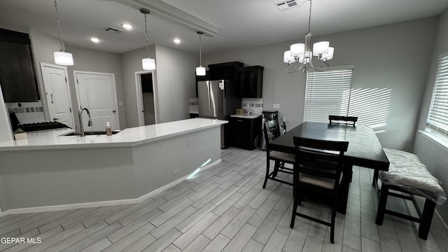 kitchen featuring stainless steel fridge, a chandelier, sink, and hanging light fixtures