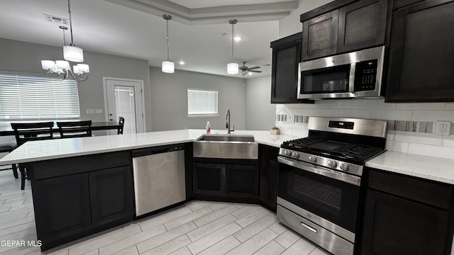 kitchen featuring ceiling fan with notable chandelier, sink, hanging light fixtures, tasteful backsplash, and stainless steel appliances