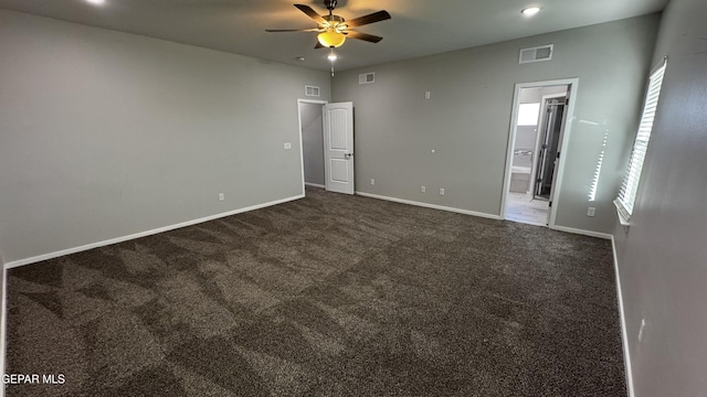 unfurnished bedroom featuring ceiling fan, dark carpet, and ensuite bathroom