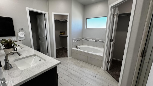 bathroom with vanity and tiled bath