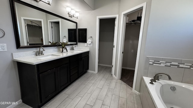 bathroom featuring tiled bath, hardwood / wood-style floors, and vanity