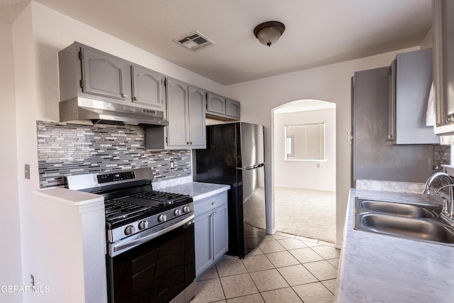 kitchen featuring black refrigerator, gray cabinetry, light colored carpet, sink, and stainless steel range with gas stovetop