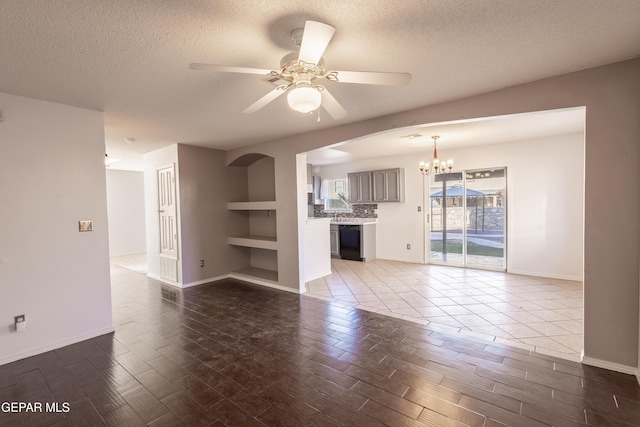 unfurnished living room featuring a textured ceiling, built in shelves, and ceiling fan with notable chandelier