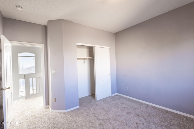 unfurnished bedroom featuring light carpet, a closet, and a textured ceiling