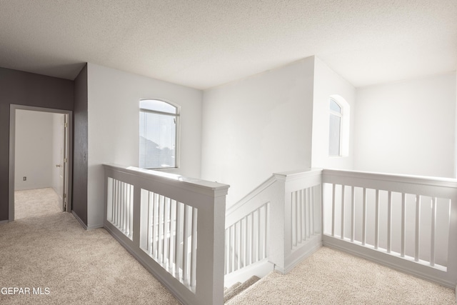 corridor featuring light carpet and a textured ceiling