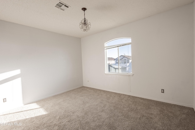 carpeted empty room featuring a chandelier and a textured ceiling