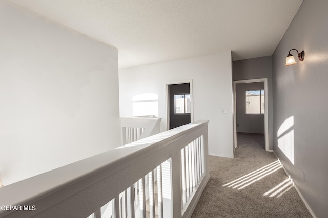 corridor featuring light carpet and a textured ceiling