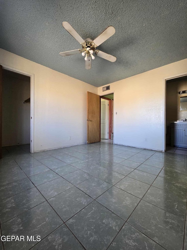 unfurnished room featuring tile patterned floors, ceiling fan, and a textured ceiling