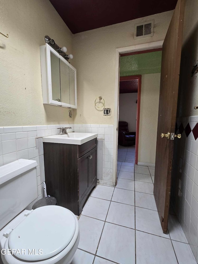 bathroom featuring tile patterned flooring, vanity, toilet, and tile walls