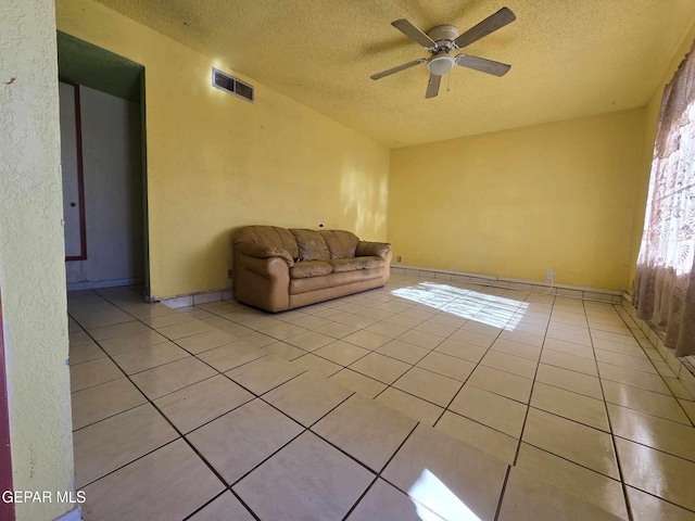 unfurnished living room with ceiling fan, light tile patterned flooring, and a textured ceiling