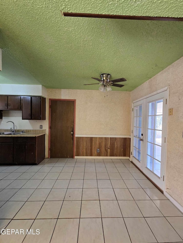 interior space with french doors, a textured ceiling, ceiling fan, sink, and light tile patterned flooring