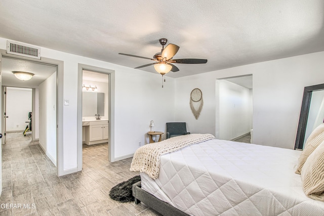 bedroom featuring ensuite bathroom, a textured ceiling, ceiling fan, sink, and light hardwood / wood-style floors