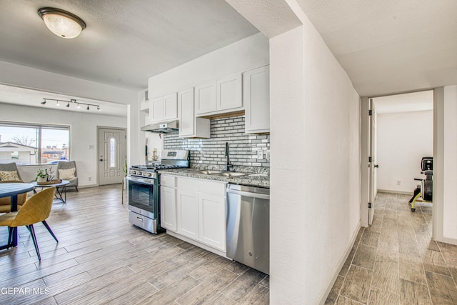 kitchen with stainless steel appliances, white cabinetry, tasteful backsplash, and sink