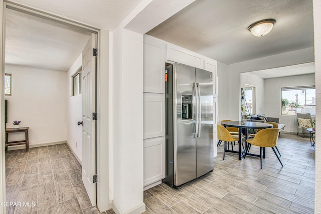 kitchen featuring white cabinets, stainless steel fridge, and a textured ceiling