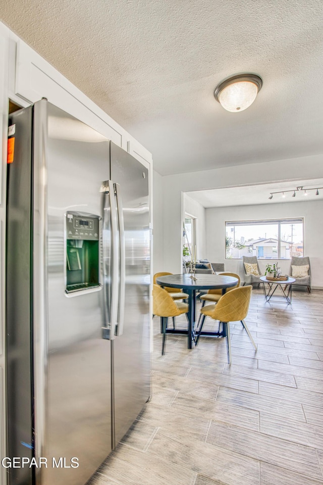 kitchen with stainless steel fridge and a textured ceiling