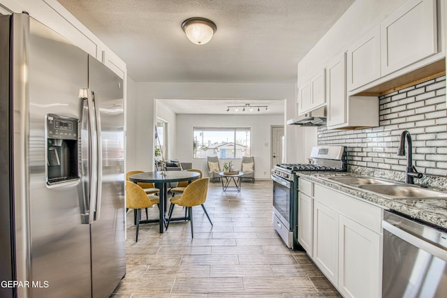 kitchen featuring white cabinets, sink, a textured ceiling, light stone counters, and stainless steel appliances