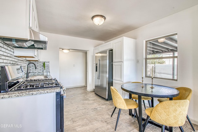 kitchen with white cabinets, appliances with stainless steel finishes, and exhaust hood