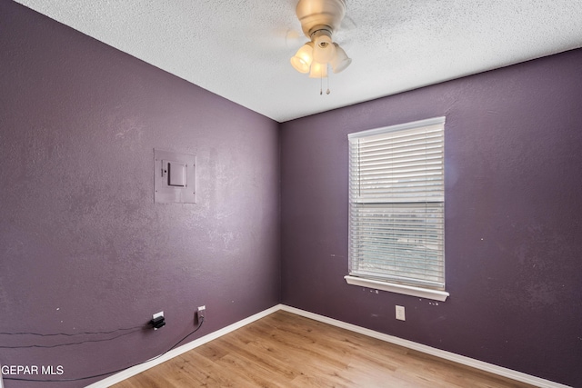 unfurnished room with ceiling fan, a textured ceiling, hardwood / wood-style floors, and electric panel